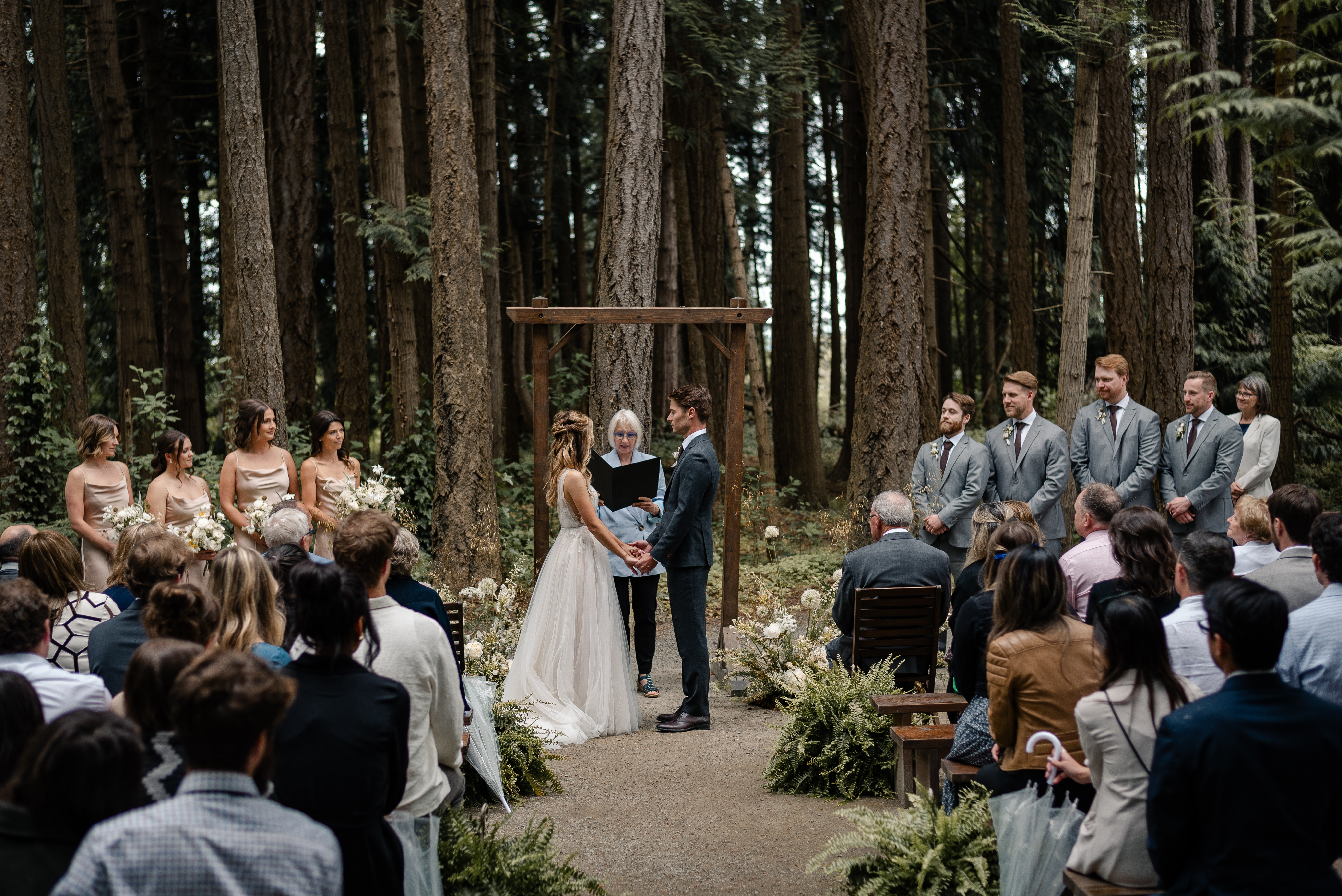 A bride a groom hold hands during their wedding ceremony at Sea Cider on Vancouver Island