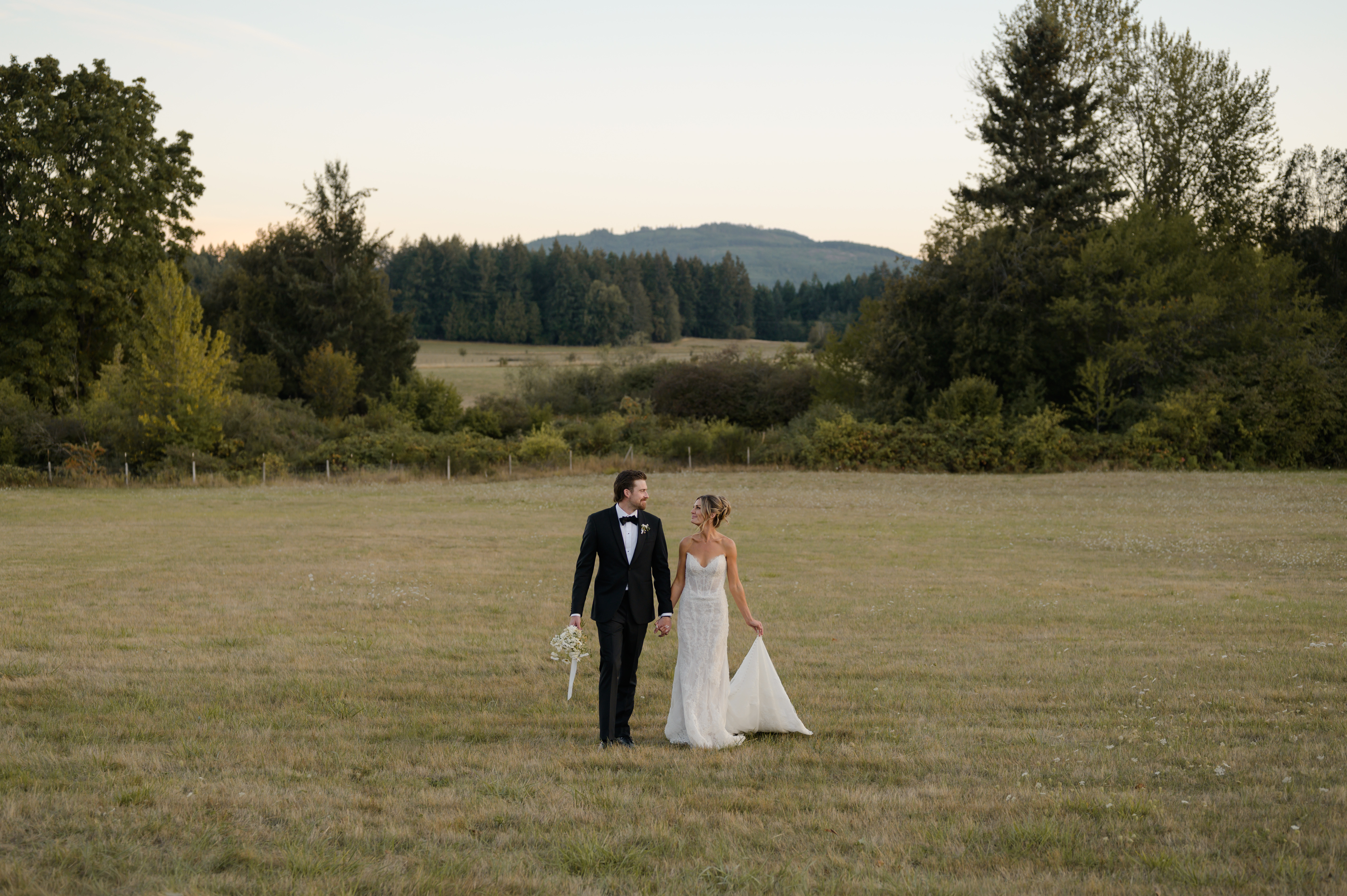 A couple walks together on their wedding day during golden hour at Keating Farm on Vancouver Island